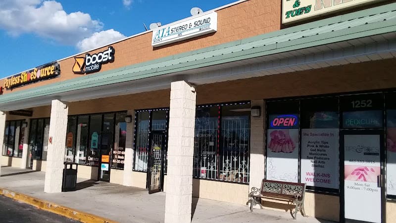 Strip mall storefront with a Boost Mobile sign and nail salon at ATA Stereo & Sound in Bartow, Florida