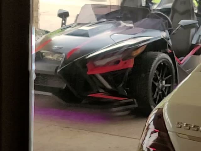 Black three-wheeled roadster with red accents in a garage at Nola Sound Solutions in Harahan, Louisiana