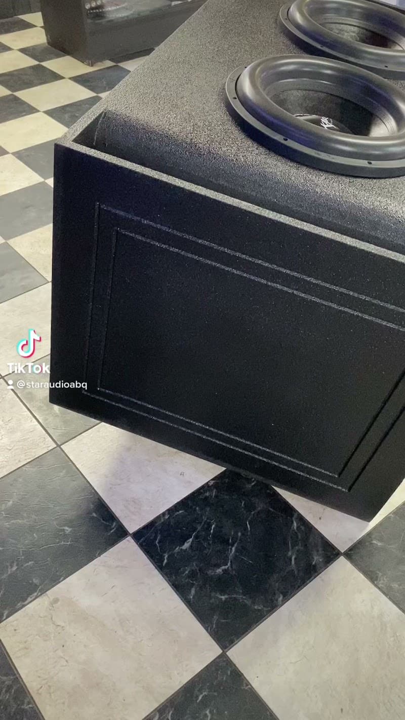 Black enclosure with two subwoofers on checkered tile floor at Star Audio in Albuquerque, New Mexico