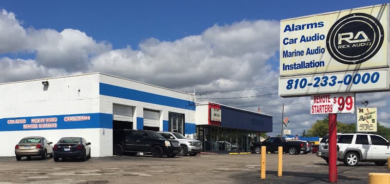 Shop front with two bay doors and parked cars at Rex Audio in Flint, Michigan