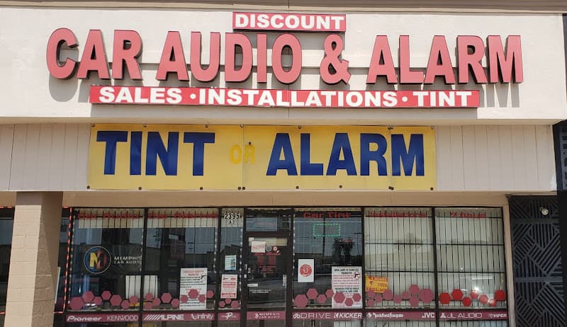 Storefront with red sign and yellow banner reading Tint or Alarm at Discount Car Audio in Houston, Texas