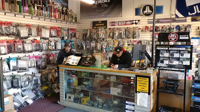 Two men behind a glass counter in a car audio shop at Performance Audio & Tint in Junction City, Kansas