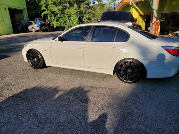 White BMW sedan with black wheels parked beside a green building at Crazy Car Audio in College Park, Maryland