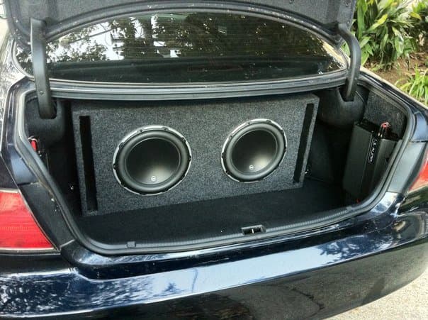 Sedan trunk with two subwoofers in a carpeted enclosure at Car Audio Connection in Harahan, Louisiana