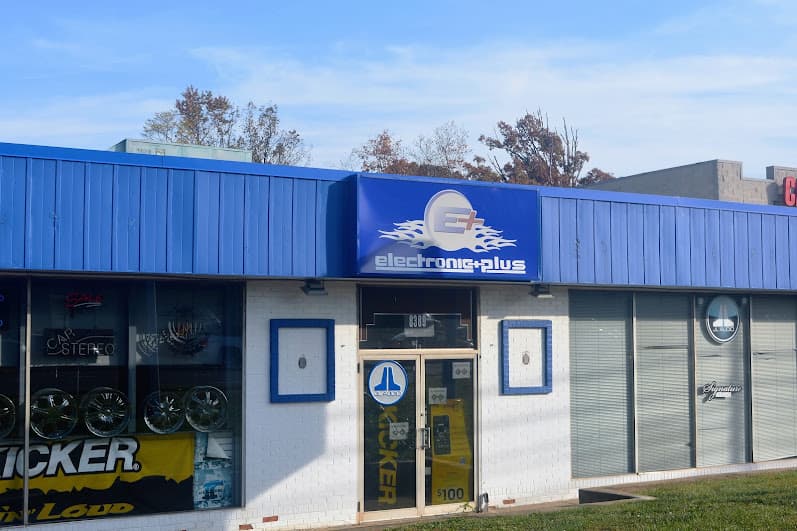 Blue storefront with a logo sign and car stereo window signs at Electronic Plus in Manassas, Virginia