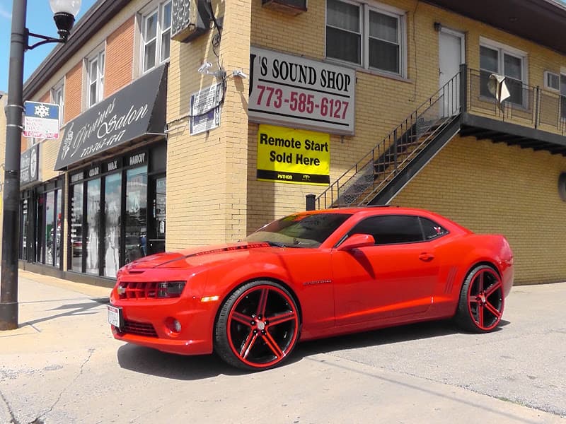Red coupe with black and red wheels parked outside a storefront at J's Sound Shop in Chicago, Illinois
