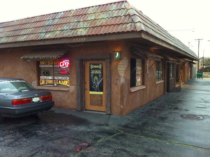 Stucco storefront with tile roof and car stereo window signs at SoundWerks Car Audio in Yucca Valley, California