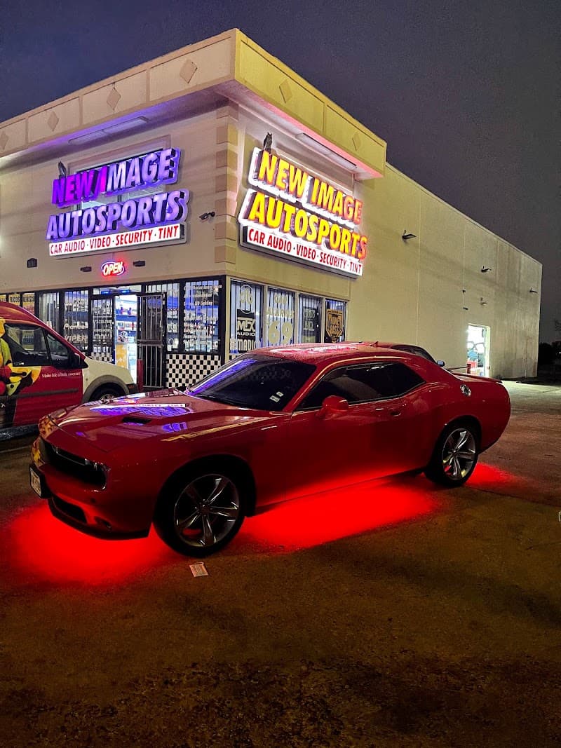 Red coupe with red underglow parked outside a lit storefront after dark at New Image Autosports in Dallas, Texas