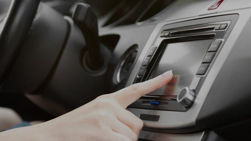 Hand touching a dash-mounted touchscreen stereo at M & M Audio Inc. in Joplin, Missouri
