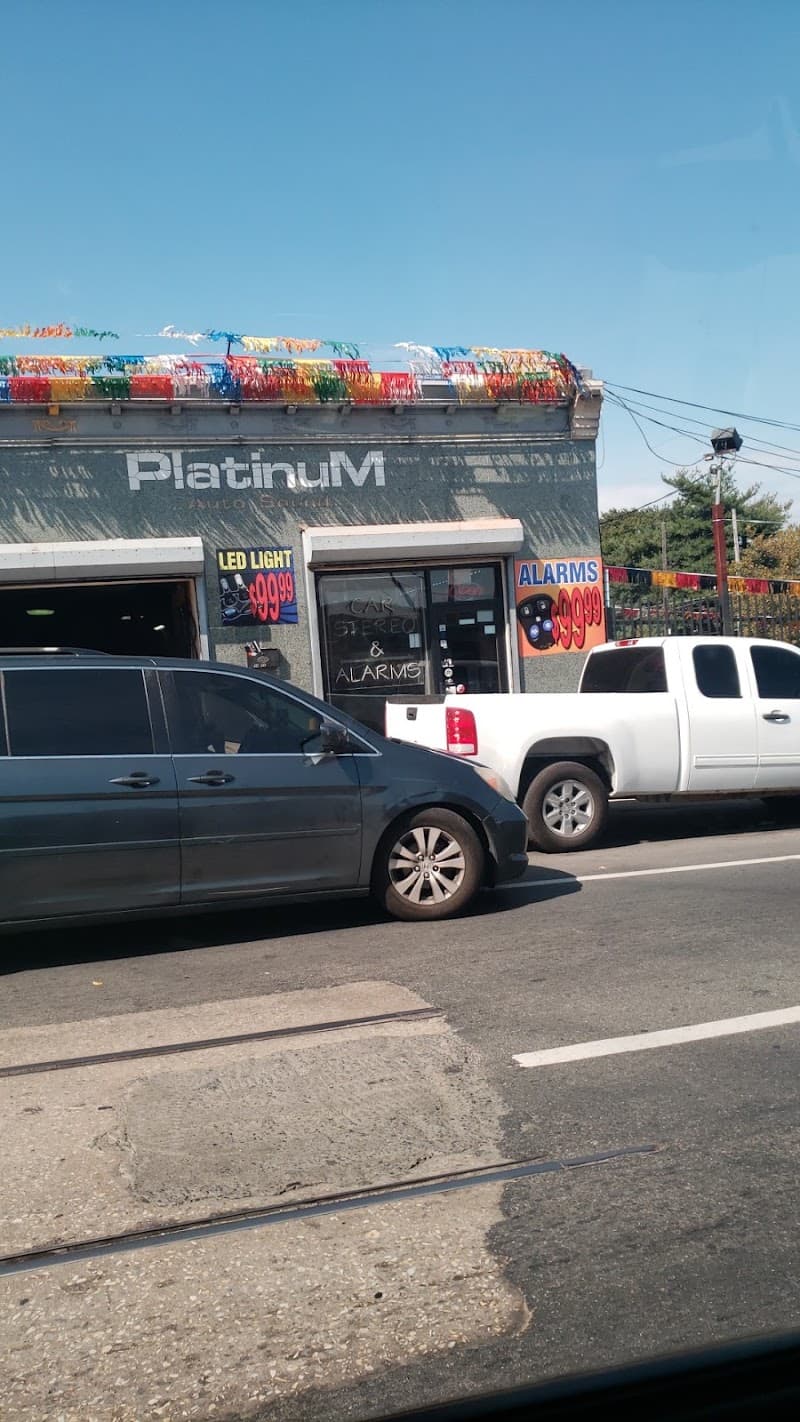 Gray storefront with car stereo window sign beside parked cars at Platinum Auto Sound in Philadelphia, Pennsylvania