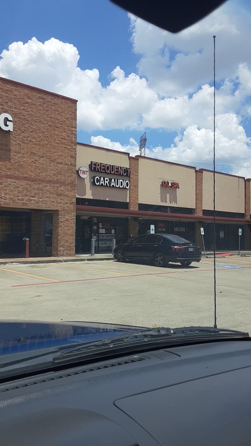 Storefront with a black sedan parked in the lot at A Frequency Car Audio in Houston, Texas
