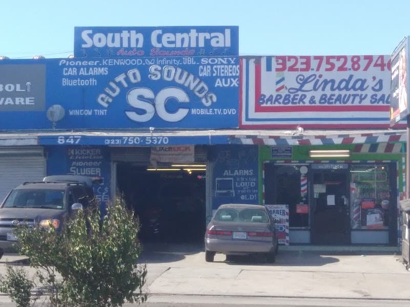 Blue storefront with car stereo signs and a barber shop at South Central Auto Sounds in Los Angeles, California