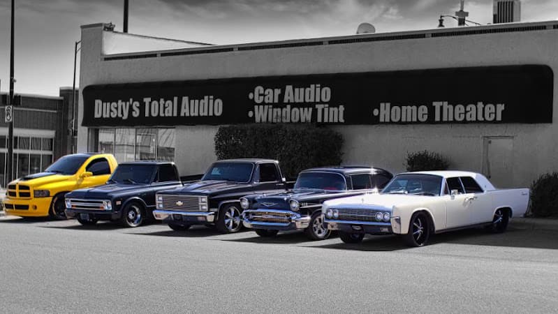 Five classic and custom vehicles parked in front of a storefront at Dusty's Total Audio in Weatherford, Oklahoma