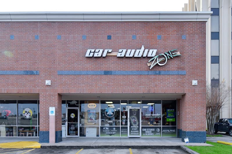 Brick storefront with car audio brand decals in windows at Car Audio Zone in Houston, Texas