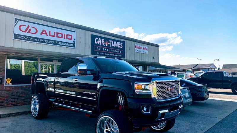 Black GMC pickup truck on large wheels in a parking lot at Car Tunes Of The Shoals in Muscle Shoals, Alabama