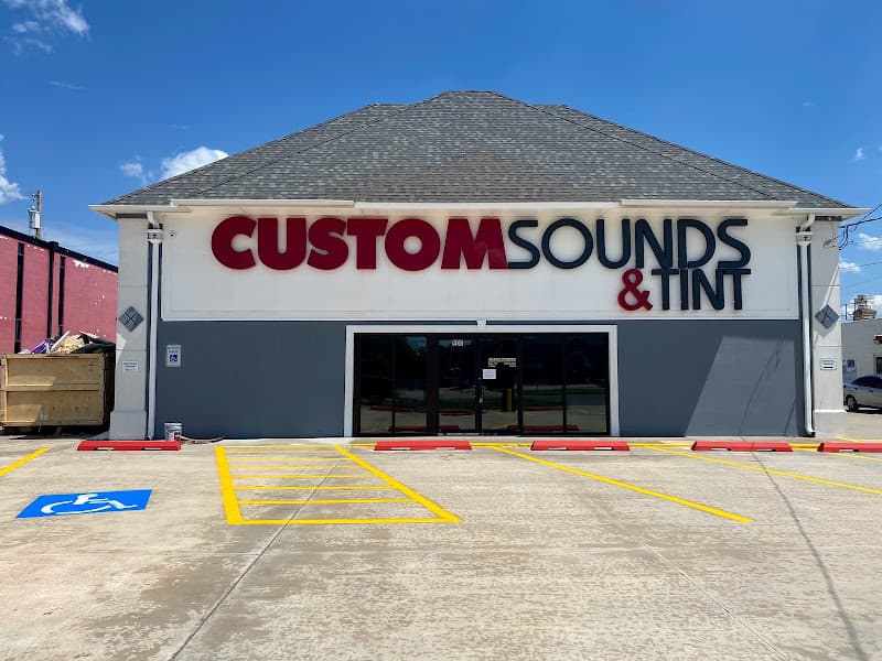 Front of shop with red and black sign above glass doors at Custom Sounds & Tint in Midwest City, Oklahoma
