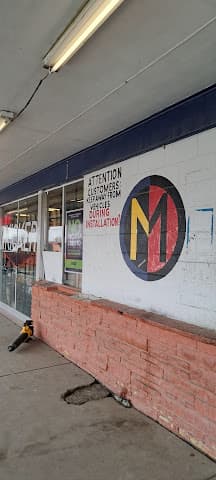 Storefront wall with red and yellow circular logo beside a sign at Guadalajara Car Audio in Tulsa, Oklahoma
