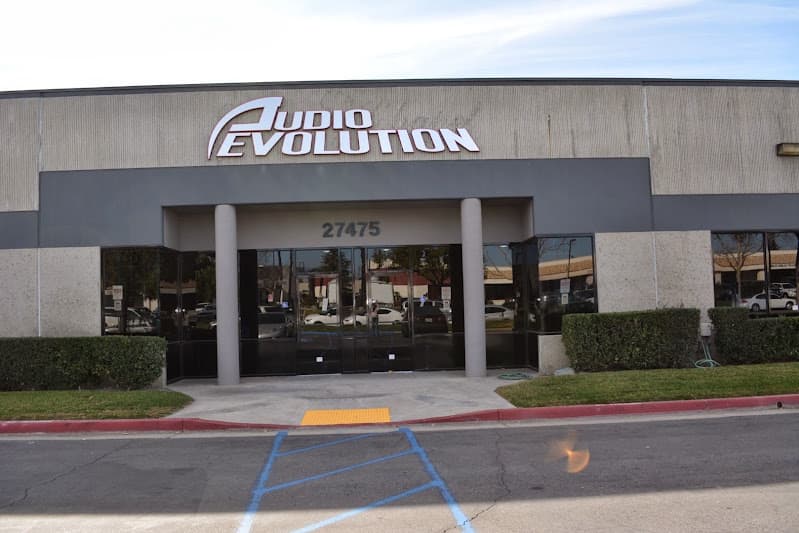 Front entrance of a beige building with a logo sign at Audio Evolution in Temecula, California