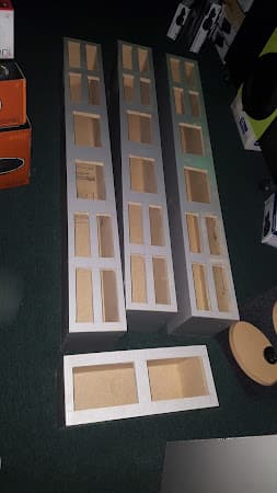 Three tall and one flat speaker enclosures on green carpet at Crazy Car Audio in College Park, Maryland