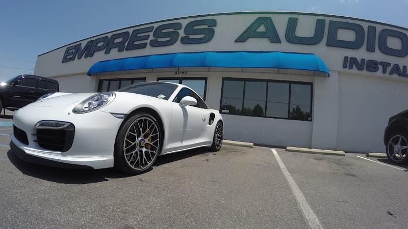 White sports car parked in front of storefront with blue awning at Empress Audio & Marine in Gulfport, Mississippi