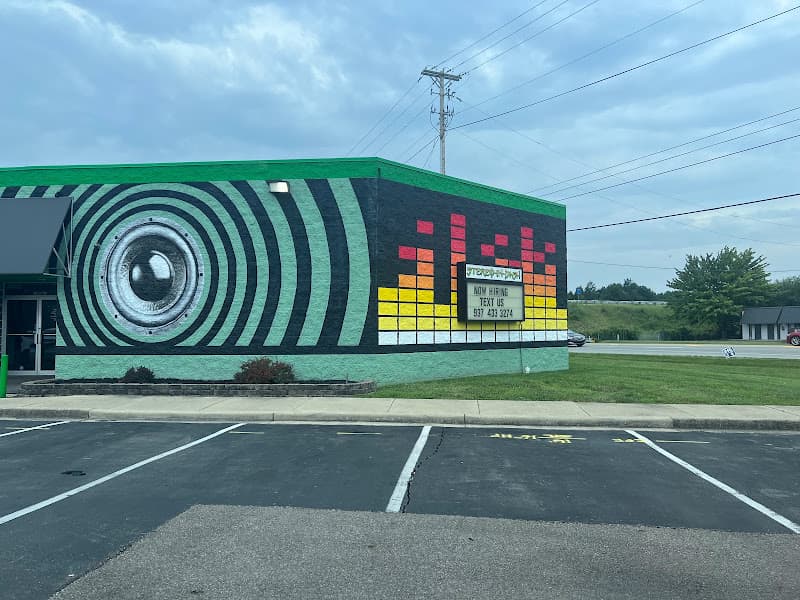 Green building with a painted speaker and equalizer mural at Stereo-in-Dash in Miamisburg, Ohio