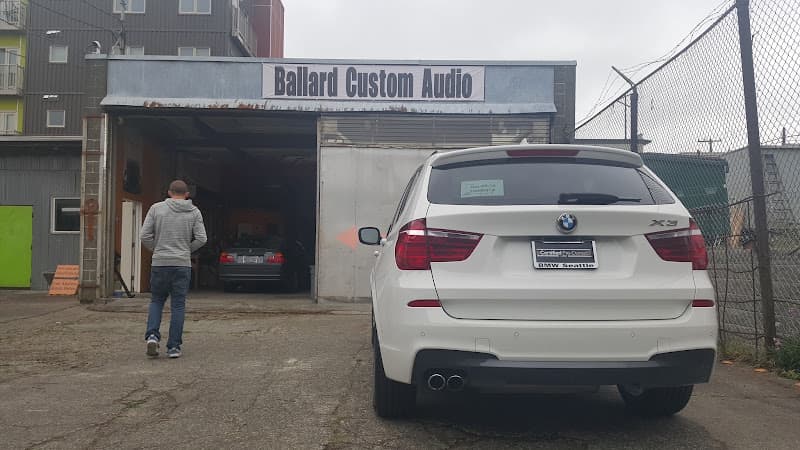 Open shop bay with a white BMW X3 parked outside at Ballard Custom Audio in Seattle, Washington