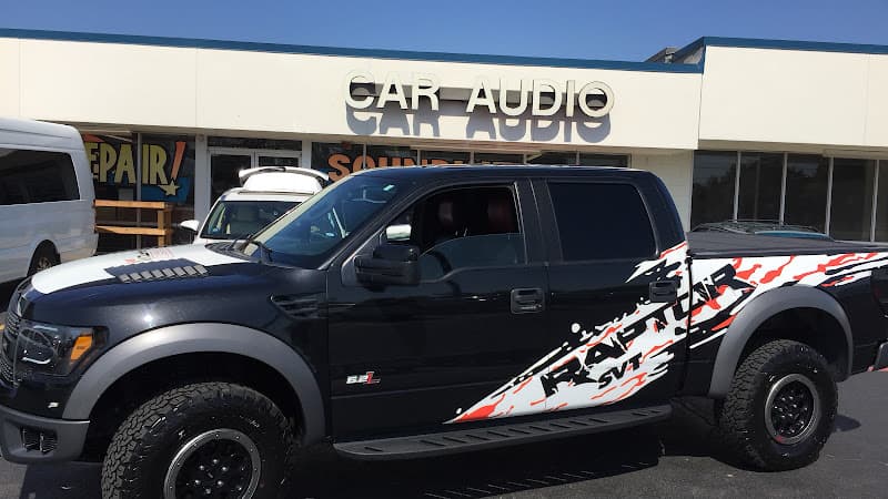 Black pickup truck with Raptor SVT graphics by a storefront at Soundwerk Car Audio Systems in Fort Worth, Texas