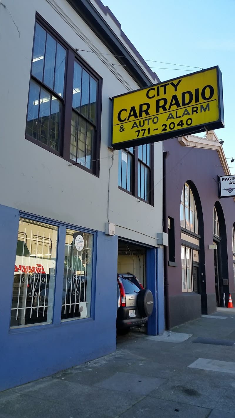 Storefront with yellow sign and an SUV entering a garage bay door at City Car Radio in San Francisco, California