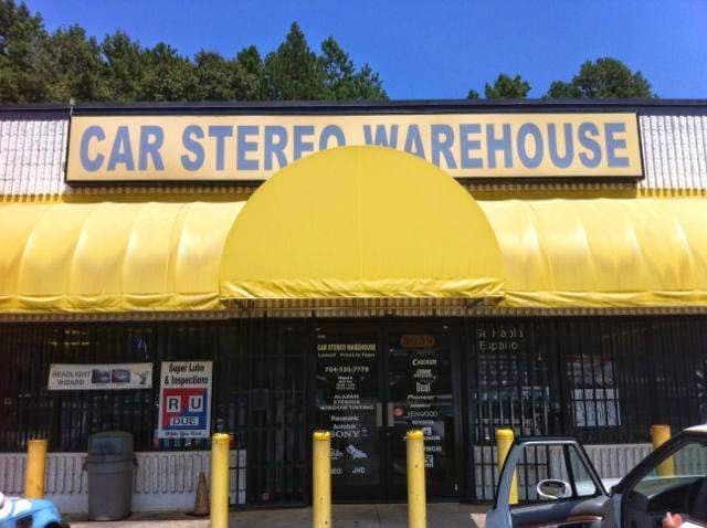 Storefront with yellow awnings, security grille and yellow bollards at Car Stereo Warehouse in Charlotte, North Carolina