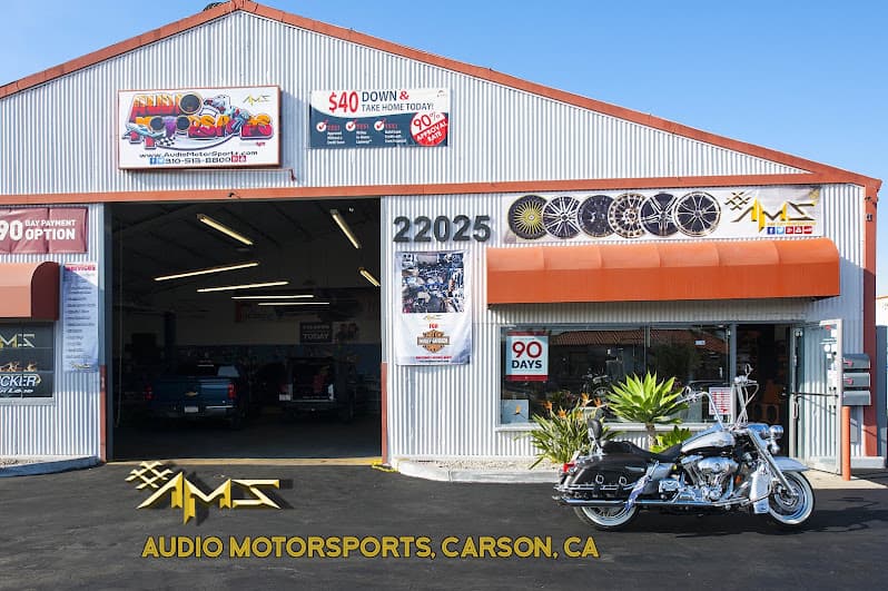 Corrugated metal storefront with orange awning and motorcycle out front at Audio MotorSport in Carson, California