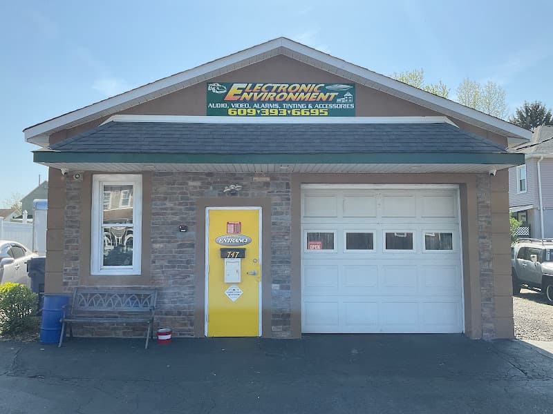 Shop exterior with yellow door and white garage door at Electronic Environment in Lawrence Township, New Jersey