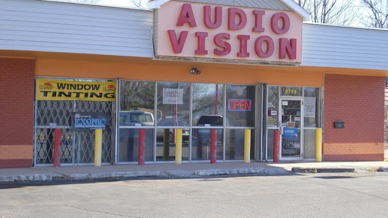 Storefront with pink lettered sign and window tint banner at Audio Vision in Indianapolis, Indiana