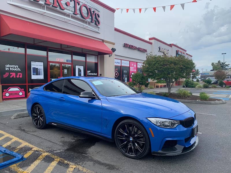 Blue coupe parked outside a store with a red awning at Car Toys in Fort Collins, Colorado