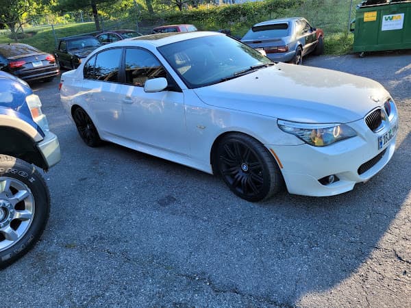 Front view of white BMW sedan with black wheels in a parking lot at Crazy Car Audio in College Park, Maryland