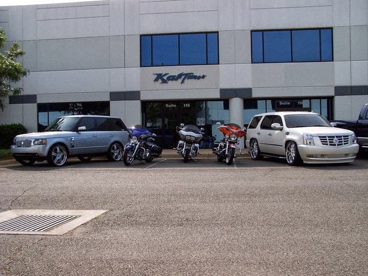 Silver SUV, two motorcycles, and white SUV parked outside an office building at Kar Tunes in Sterling, Virginia