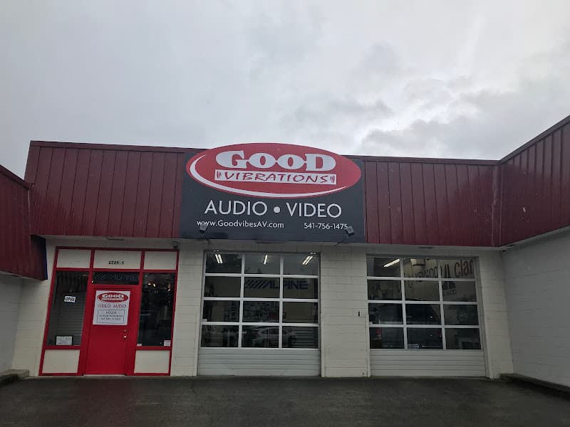 Storefront with red and black sign and two overhead bay doors at Good Vibrations Audio Video in North Bend, Oregon