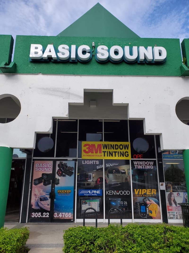 Green storefront with white sign and window tinting banner at Basic Sound and Tint in Miami, Florida