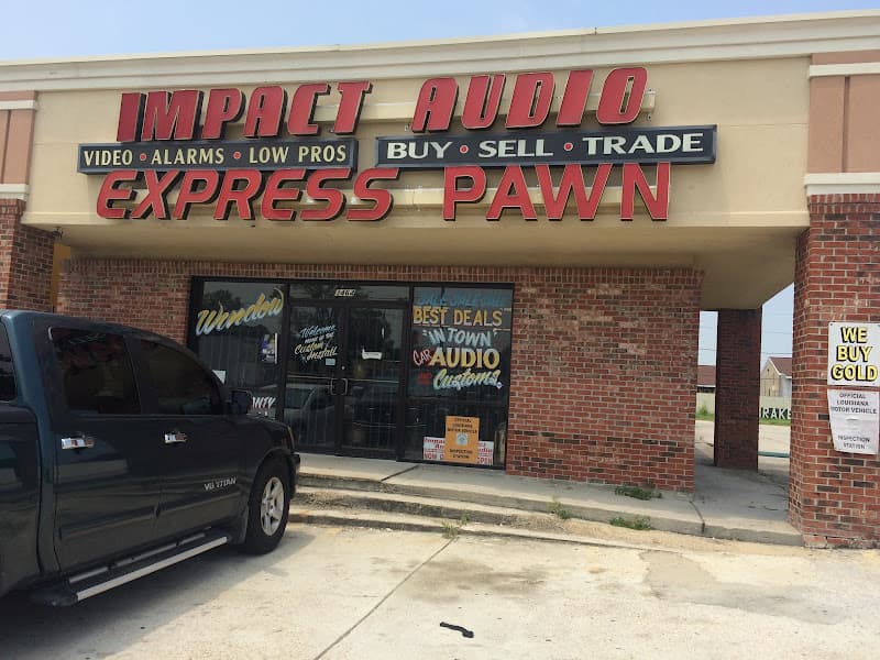 Brick storefront with red signs and a dark pickup outside at Impact Audio in Marrero, Louisiana