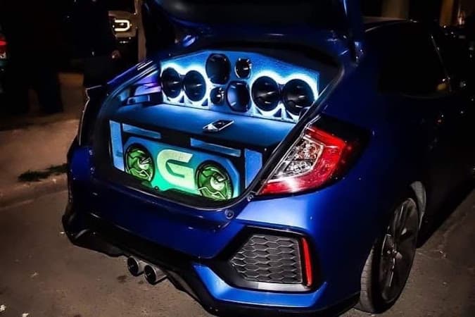 Blue hatchback with speaker enclosures in its open trunk at Make Some Noise in El Paso, Texas
