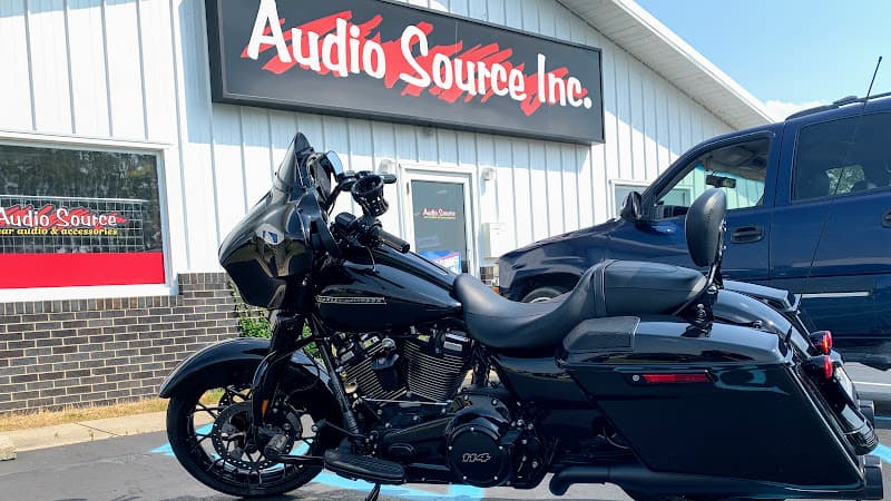 Black motorcycle parked in front of a white storefront building at Audio Source in Columbus, Indiana