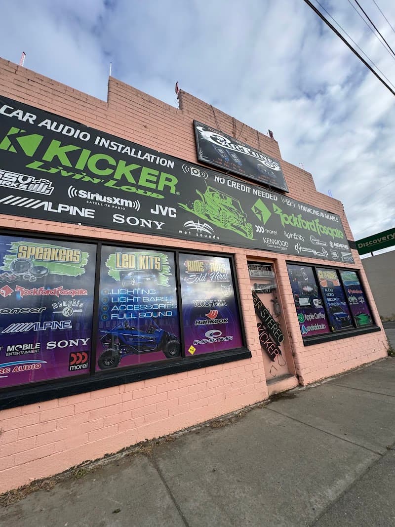 Pink brick storefront with a car audio installation banner at Car Tunes in Grants Pass, Oregon