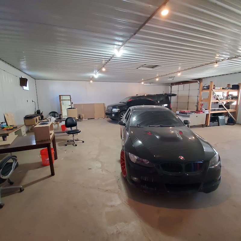Black coupe with red wheels parked in a large shop at RBA Mobile Electronics in Plano, Illinois
