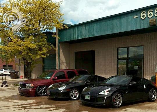 Red SUV and two black cars parked outside a building at Absolutely Creative Customs in Boulder, Colorado