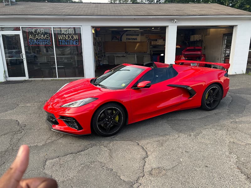 Red sports convertible outside a shop with car alarm and tint signs at Tint Works/Sound Works in Hamden, Connecticut