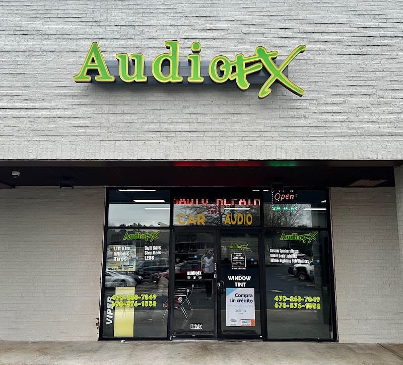 Storefront with glass doors and green signs on a white brick wall at Audio FX in Lawrenceville, Georgia