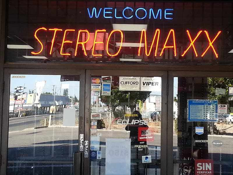 Glass entry doors under a red and blue neon Welcome sign at Stereo Maxx of Hayward in Hayward, California