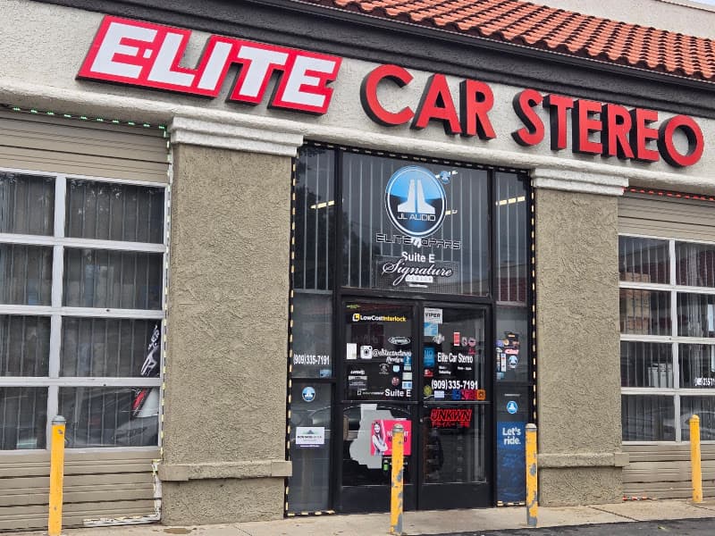 Storefront with red signage and large glass bay windows at Elite Car Stereo in Redlands, California
