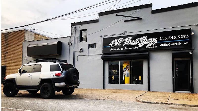 Gray storefront with a silver SUV parked outside at All That Jazz Sound & Security in Philadelphia, Pennsylvania
