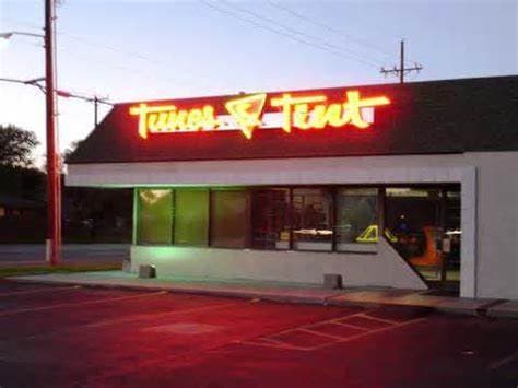 Neon sign on a low storefront after dark at Tunes & Tint in Amarillo, Texas