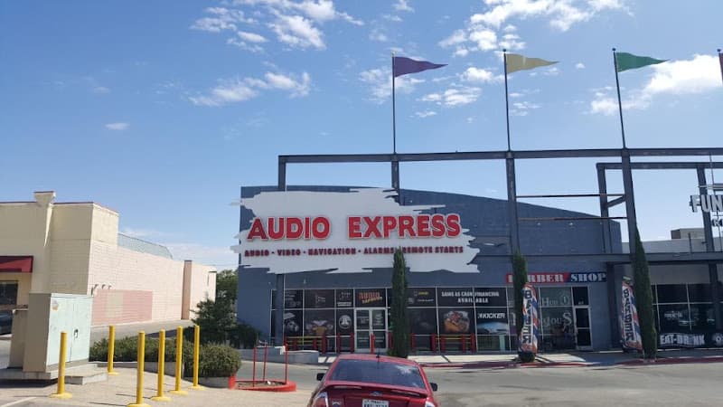 Storefront with red sign and a red car in the parking lot at Audio Express in El Paso, Texas